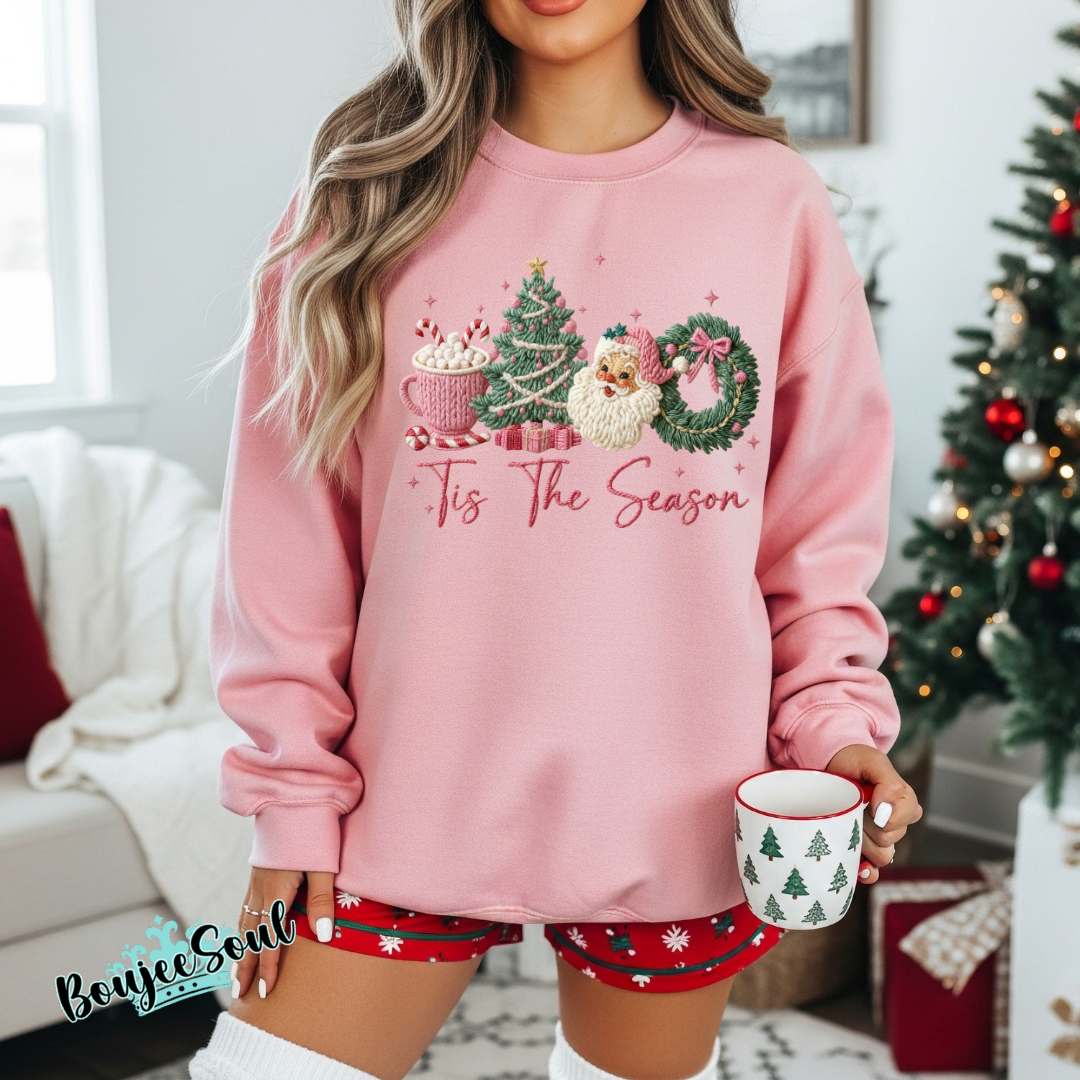 Pink Tis the Season faux crochet Christmas sweatshirt with Santa, hot cocoa, tree, and wreath design.